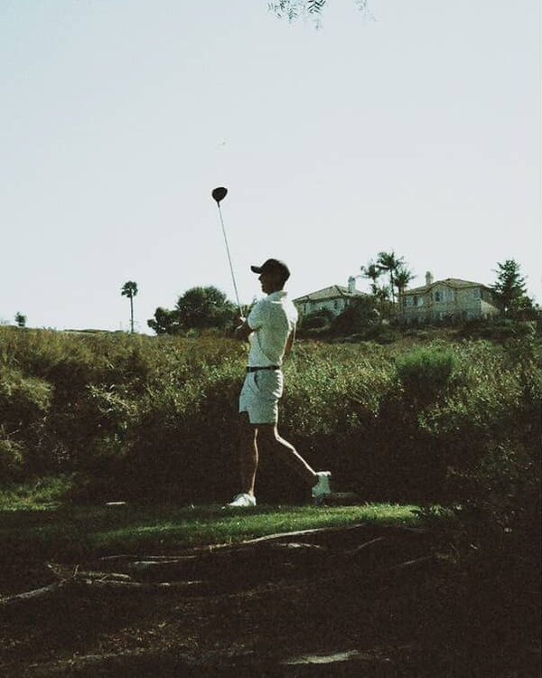 Brennan at the top of his backswing on a tee box, driver overhead.